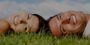 a couple laying on grass smiling into the camera