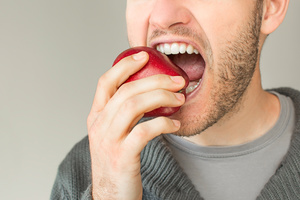 closeup of a bearded man biting into an apple